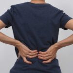 A person holding with lower back discomfort