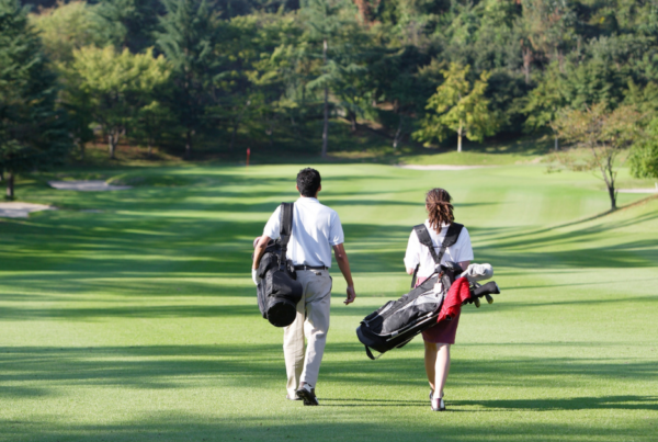 Two golfers walking on a course to stay active and prevent golf back pain