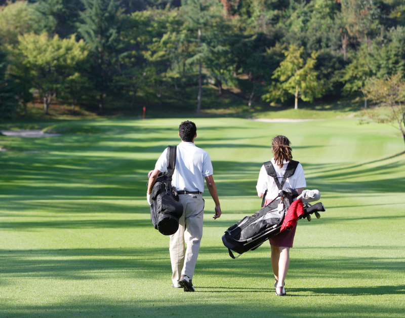 Two golfers walking on a course to stay active and prevent golf back pain